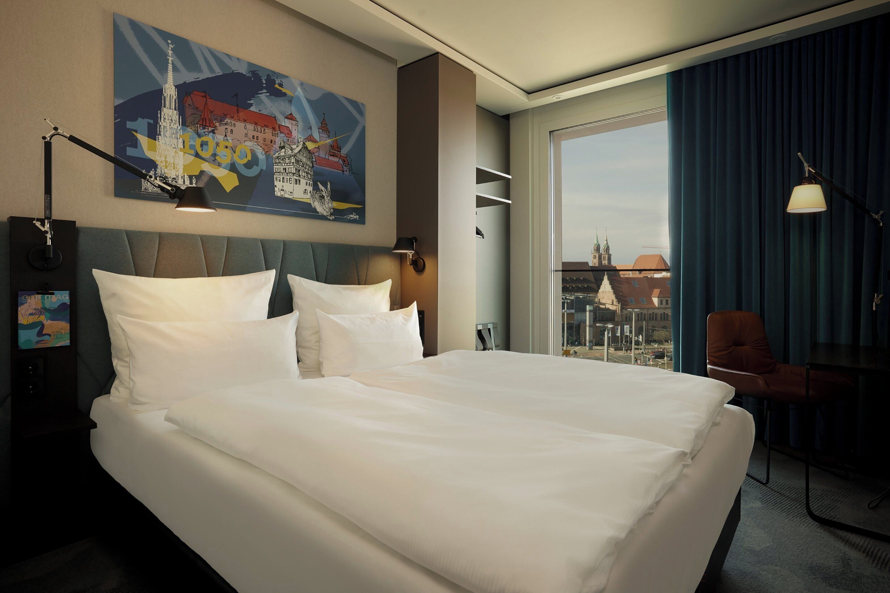 Habitación de hotel con una cama grande, vistas a la ciudad, un cuadro en la pared y un escritorio con una silla.