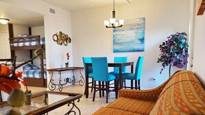 A living room with a sofa, a dining table with chairs, a chandelier, a painting, and a potted plant. - Sun Ray #1A - Pet Friendly, 3min Walk to Beach (South Padre Island)