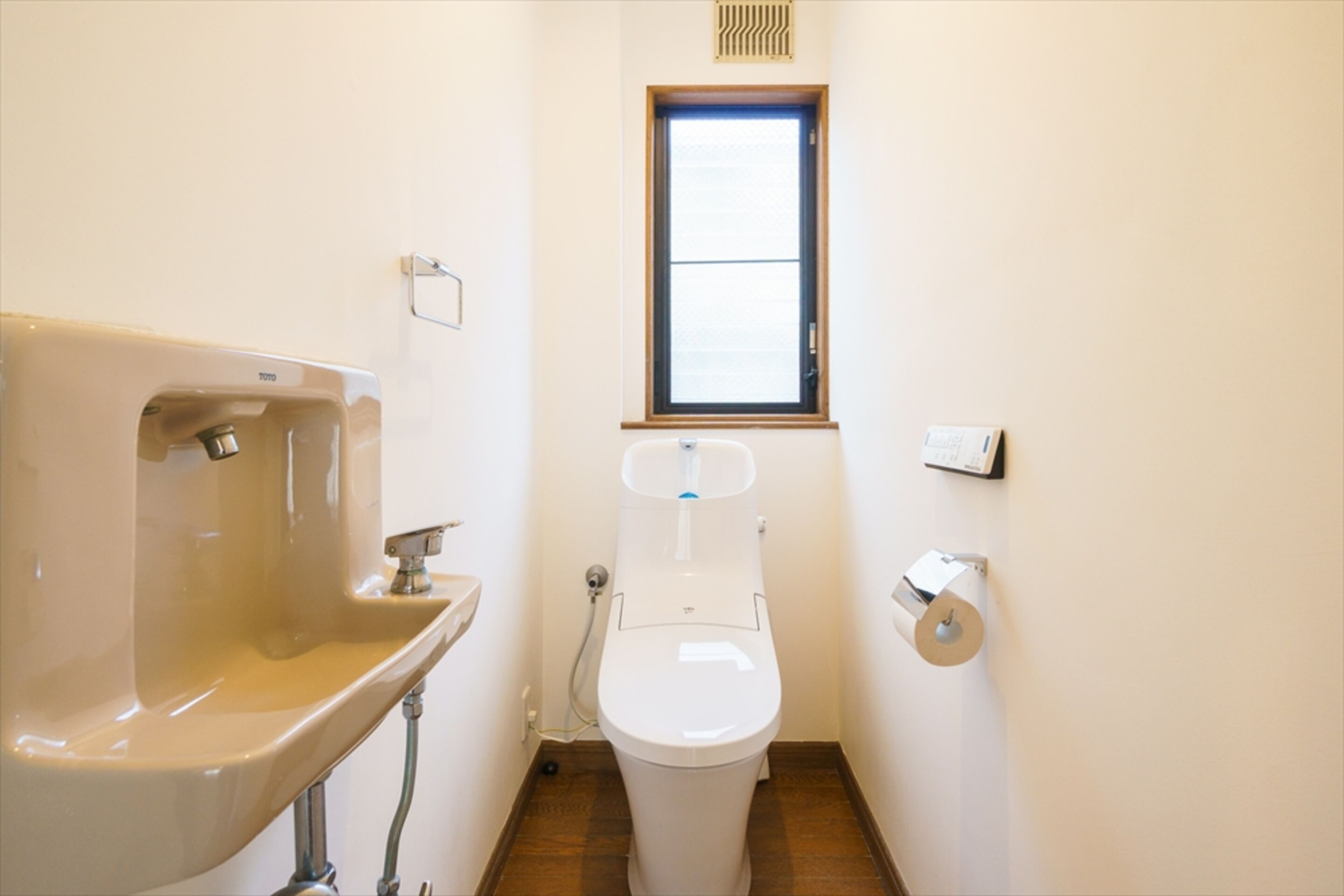 A small bathroom with a sink, toilet, and window.
