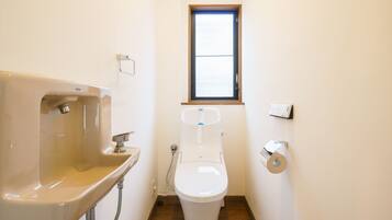 A small bathroom with a sink, toilet, and window.
