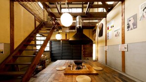A traditional Japanese interior with wooden floors, a central hearth, and a staircase.