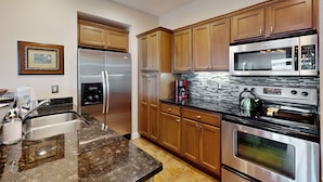 A modern kitchen with stainless steel appliances, wooden cabinets, and a granite countertop. - Relaxing condo with sweeping valley views, deck, and fireplace (Sugar Mountain)