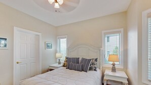 A bedroom with a bed, two bedside tables, a nightstand, a ceiling fan, and a door. - Relaxing condo with sweeping valley views, deck, and fireplace (Sugar Mountain)