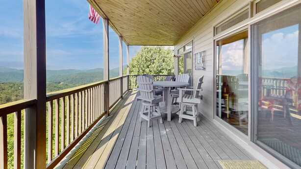 A wooden deck with a table and chairs, overlooking a scenic landscape. - Relaxing condo with sweeping valley views, deck, and fireplace (Sugar Mountain)