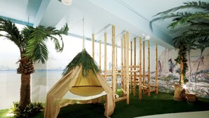 Una habitación con una hamaca colgante, una palmera y un mural de una playa.