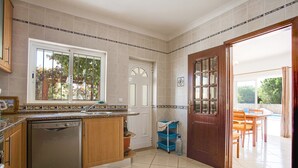 Una cocina con lavavajillas, ventana, puerta y vistas al exterior.