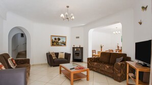 Una sala de estar con sofá, mesa de centro, mueble para televisión, chimenea y escalera.
