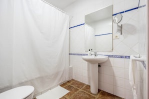 A bathroom with a white toilet, a sink, a shower curtain, and a mirror.