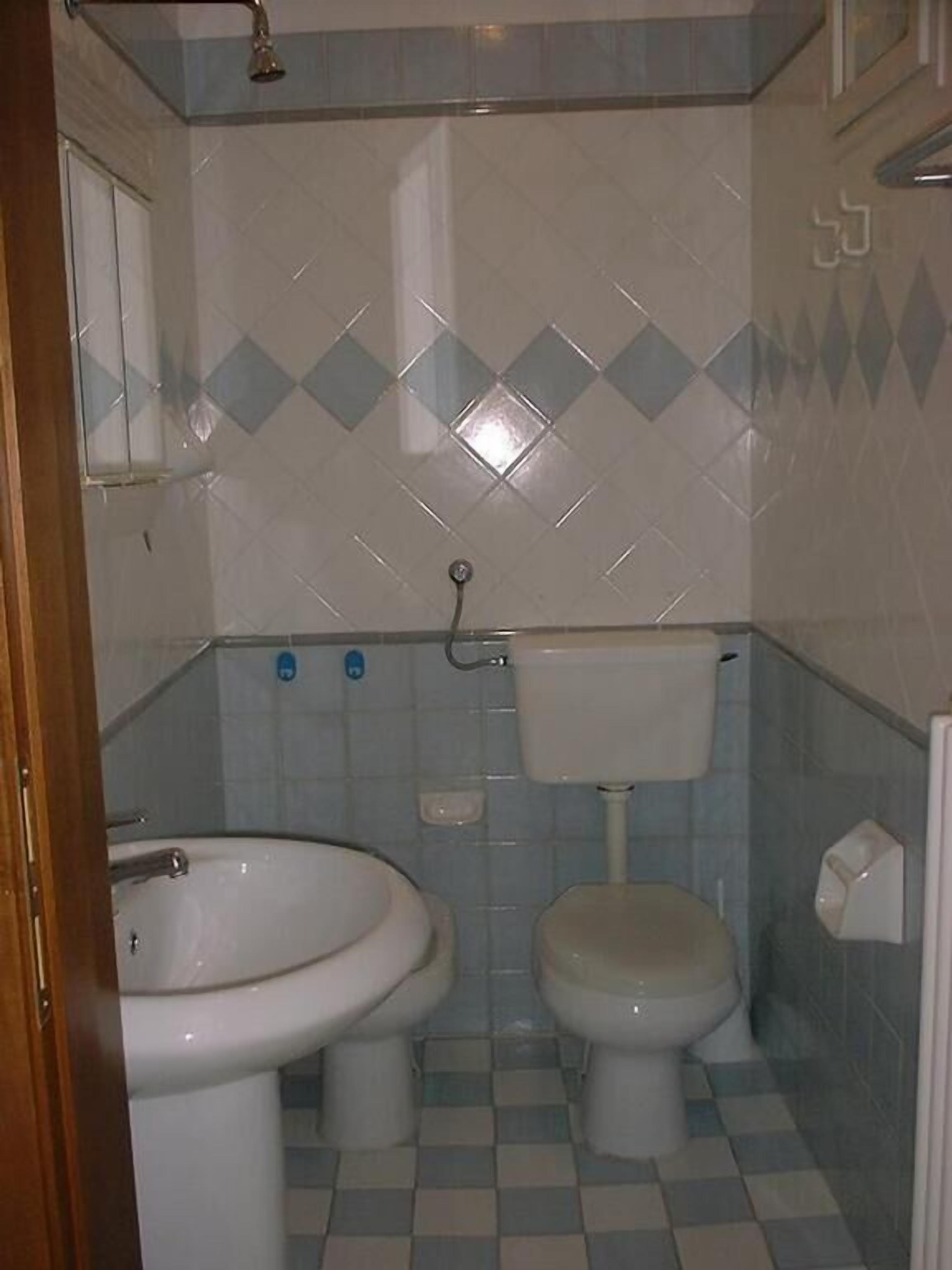 A bathroom with two toilets, a sink, and a shower.