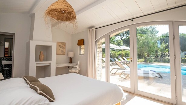 Quarto com cama grande, escrivaninha e vista para uma piscina.