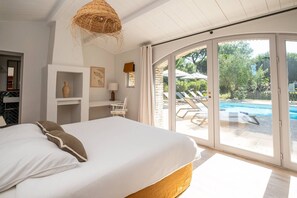 Ein Schlafzimmer mit einem großen Bett, einem Schreibtisch und Blick auf einen Swimmingpool.