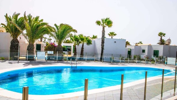 En swimmingpool omgiven av palmer och vita byggnader.