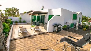 Ett modernt hus med en uteplats, utomhusmöbler och ett område för grillning.