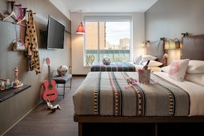 Relax in a spacious room with a large bed, seating area, and city view through a large window.