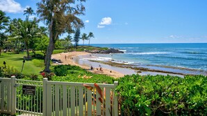 A beach view with a sign indicating the gate is closed. - Sunrise Serenity| 2BR Oceanfront Condo With AC (Kapaa)