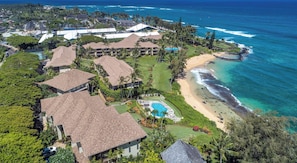An aerial view of a resort with multiple buildings, a swimming pool, and a beach.