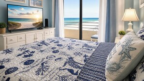 Une chambre avec un lit, une télévision, un balcon donnant sur la plage et une lampe.