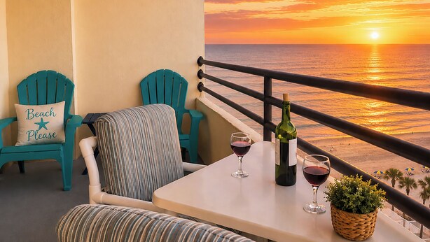 Un balcon avec deux chaises, une table, deux verres à vin, une bouteille et une plante.