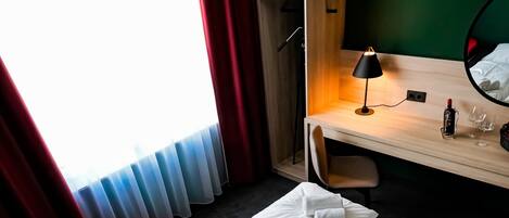 A hotel room with a bed, a desk, a chair, and a red chair.