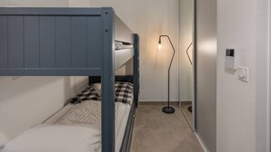 Ein kleines, gemütliches Zimmer mit Etagenbett, Stehlampe und Spiegel.