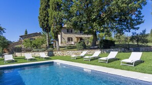 Zona piscina con lettini e un edificio in pietra sullo sfondo.