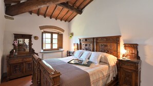 Una camera da letto tradizionale con un letto in legno, una cassettiera e una finestra con persiane.