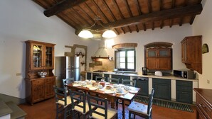 Una cucina rustica con mobili in legno, un tavolo da pranzo apparecchiato per quattro persone e un camino in pietra.