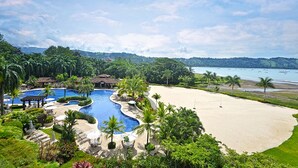 Un resort con una gran piscina, una playa de arena y vistas al océano.