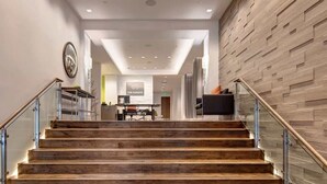 Una escalera de madera con barandillas de vidrio que conduce a una recepción con un cartel que dice 'THE PARKITE'.