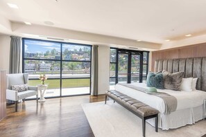 Une chambre spacieuse avec une grande fenêtre, un lit doté de plusieurs oreillers, un banc et une chaise.