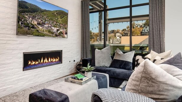 Una sala de estar moderna con chimenea, un ventanal con vistas y un televisor de pared.