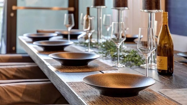 A long dining table with multiple plates and wine glasses, a bottle of wine, and a candle. - Abode at Parkite #24, hot tub, balcony overlooking Main Street, gym, luxury condo (Park City)