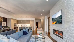 A modern living room with a fireplace, a dining area, and a kitchen in the background. - Abode at Parkite #24, hot tub, balcony overlooking Main Street, gym, luxury condo (Park City)