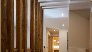 A hallway with wooden paneling, a radiator, and a kitchen area in the distance. - Sport Apart (Zell am Ziller)
