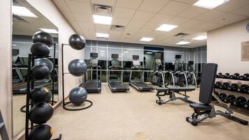 Uma academia com esteiras, bolas de exercício e halteres.