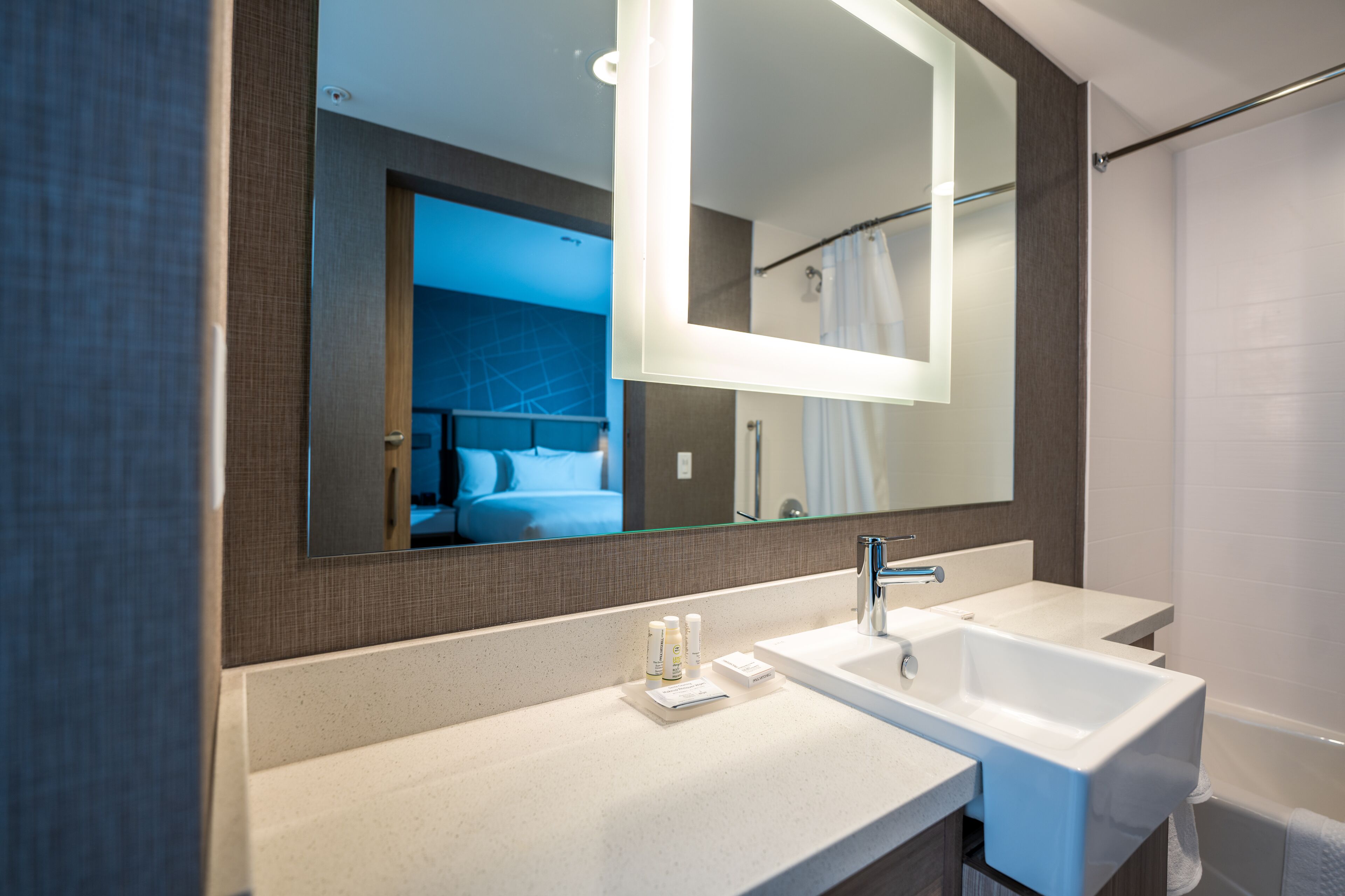 A modern bathroom with a large mirror, two sinks, and a shower.