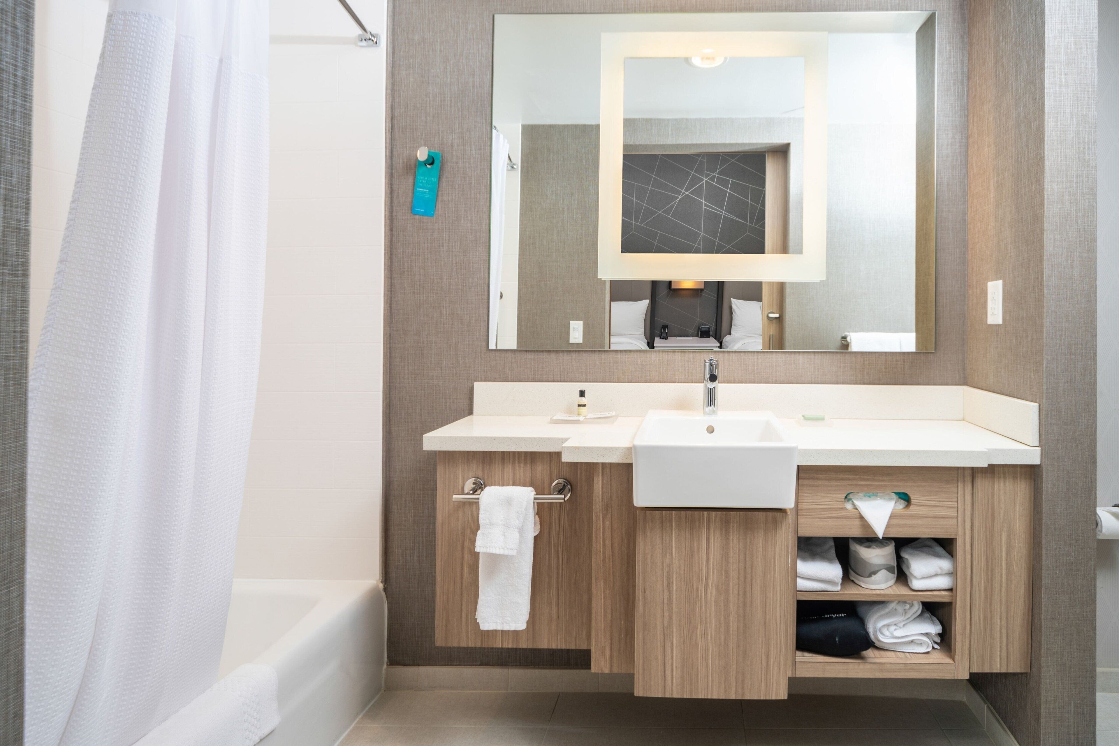 Un baño moderno con bañera, dos lavamanos, un espejo grande y un perchero para toallas.