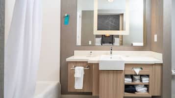 Un baño moderno con bañera, dos lavamanos, un espejo grande y un perchero para toallas.