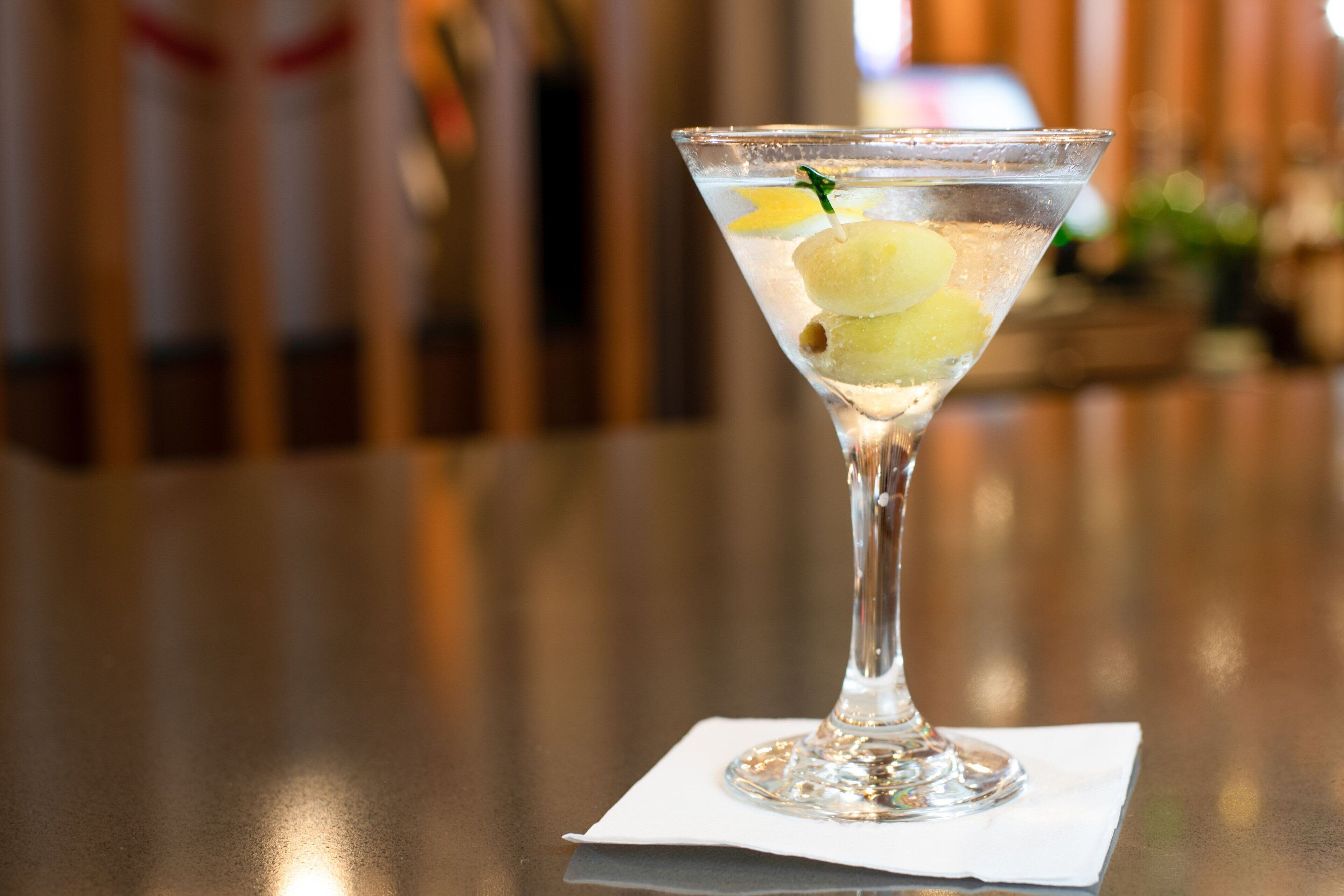 Martini-lasi, jossa on sitruunaviipaleita ja mintunlehti koristeena valkoisella servietillä.