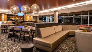 A modern lobby with a seating area, a bar, and a large window providing a view of the city at night. - SpringHill Suites by Marriott Kenosha (Kenosha)
