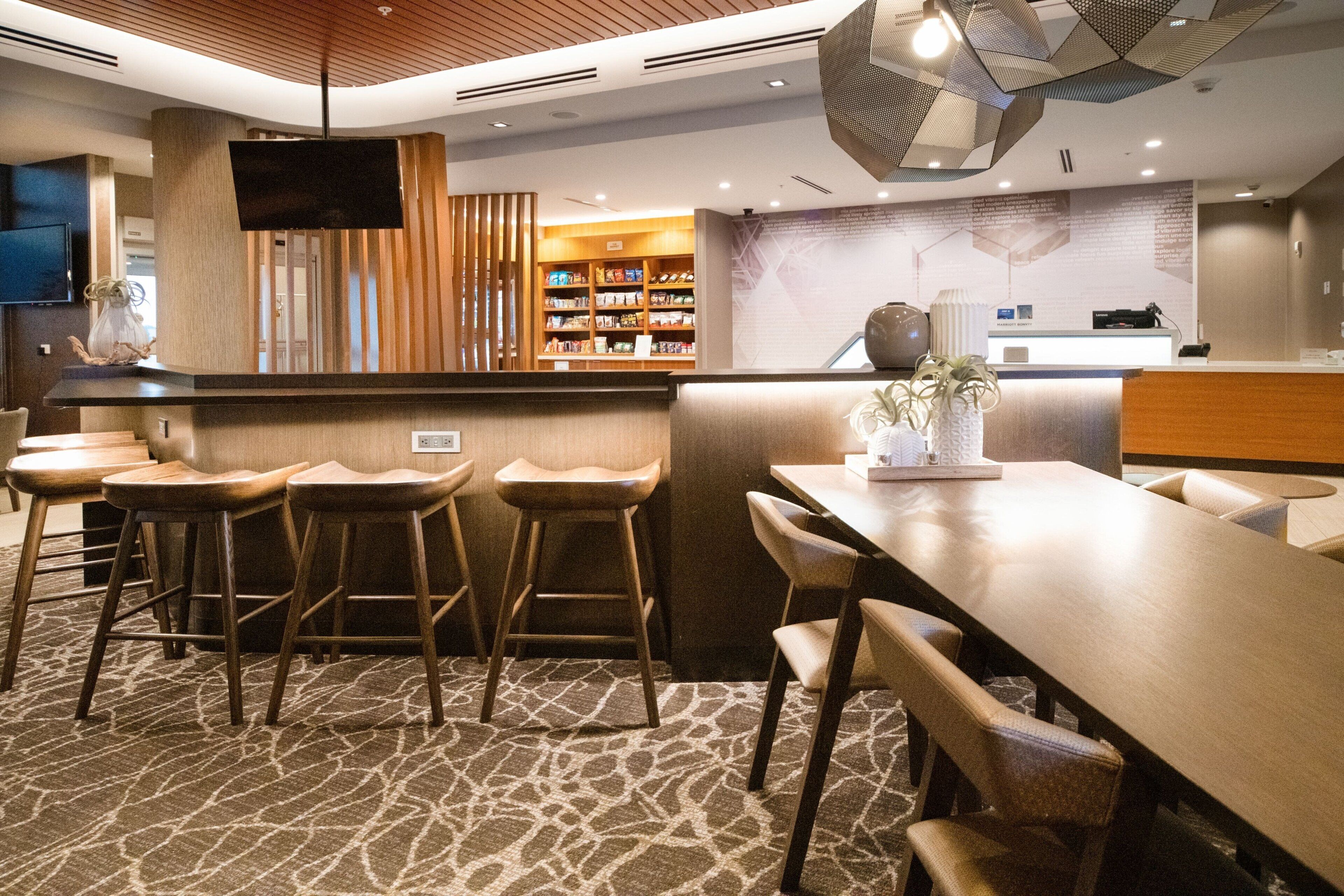 A modern hotel lobby with a reception desk, bar area, and seating.