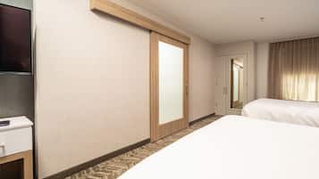 A hotel room with a bed, a desk, a television, a sliding door, and a window with curtains.