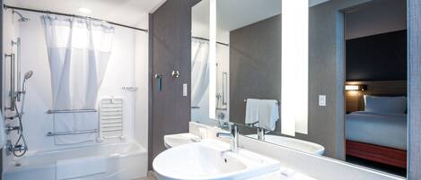 Un baño moderno con bañera, un lavamanos amplio y un espejo.