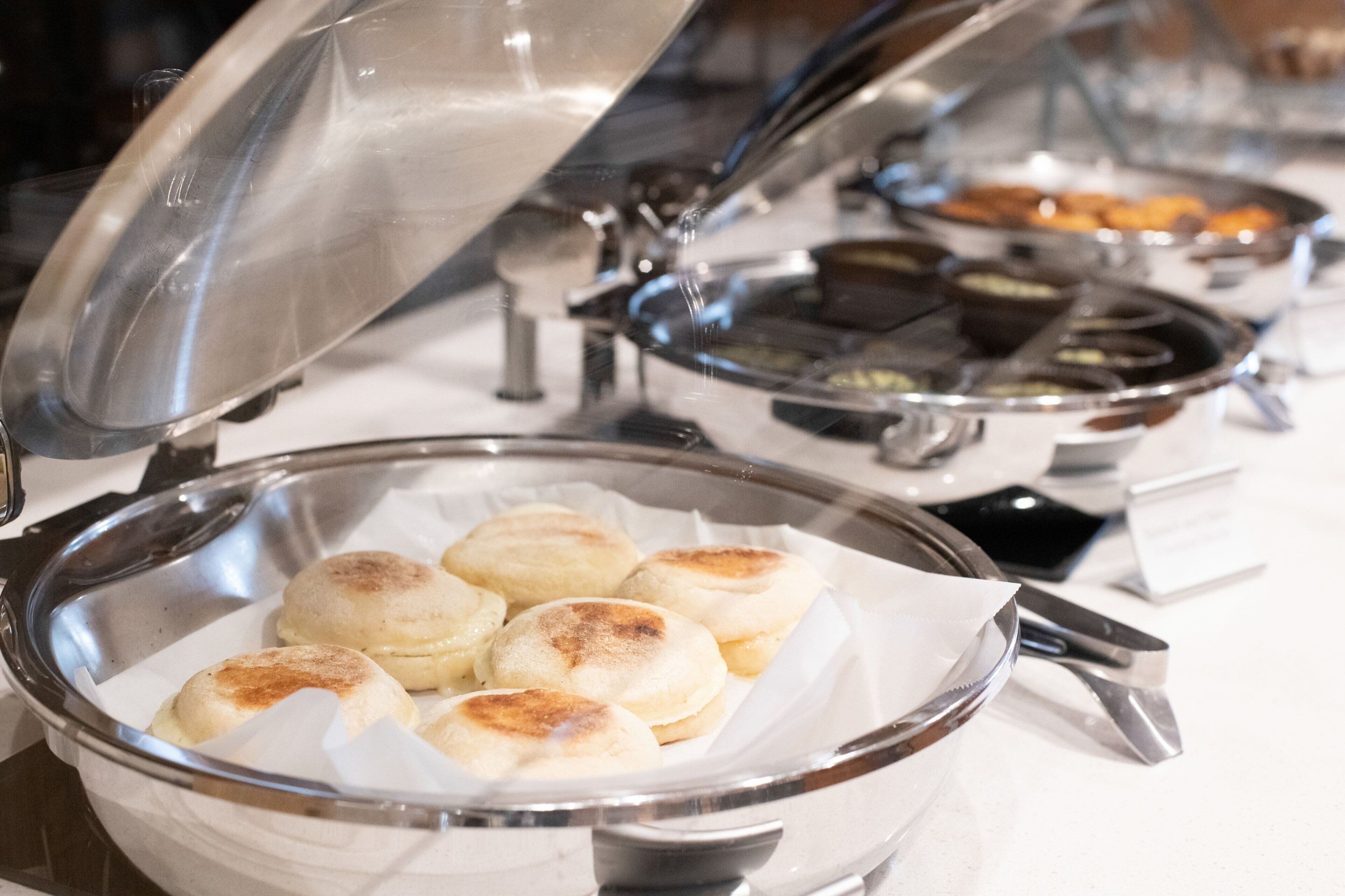 Un buffet proposant une variété de plats, notamment un plat de petits pains cuits à la vapeur et d’autres mets.