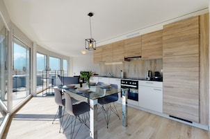 Una cocina moderna con una mesa de comedor de cristal, armarios de madera y vistas a la ciudad.