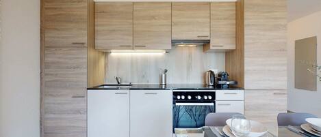 Una cocina moderna con armarios de madera, una estufa y un comedor con una mesa dispuesta para dos.