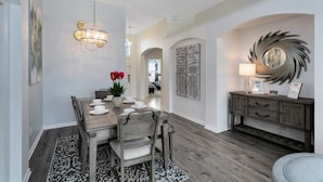 A dining area with a wooden table set for four, a chandelier, and a decorative wall piece. - Immaculate 4 Bedrooms 3 Bathroom In Windsor Palms Villa by RedAwning (Kissimmee)