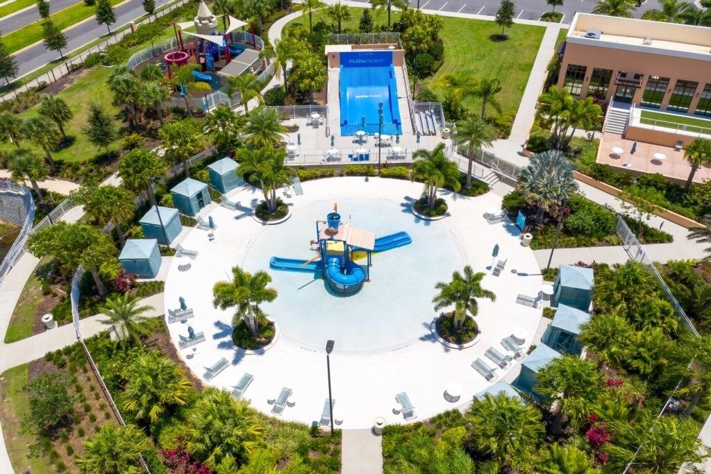 Vista aérea de um resort com piscina central, espreguiçadeiras e palmeiras.