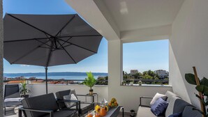 En balkon med havudsigt, møbleret med en sofa, stole og et bord med frugt og drikkevarer.