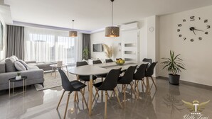 En moderne stue med en grå sofa, et spisebord med sorte stole og et stort vægur.